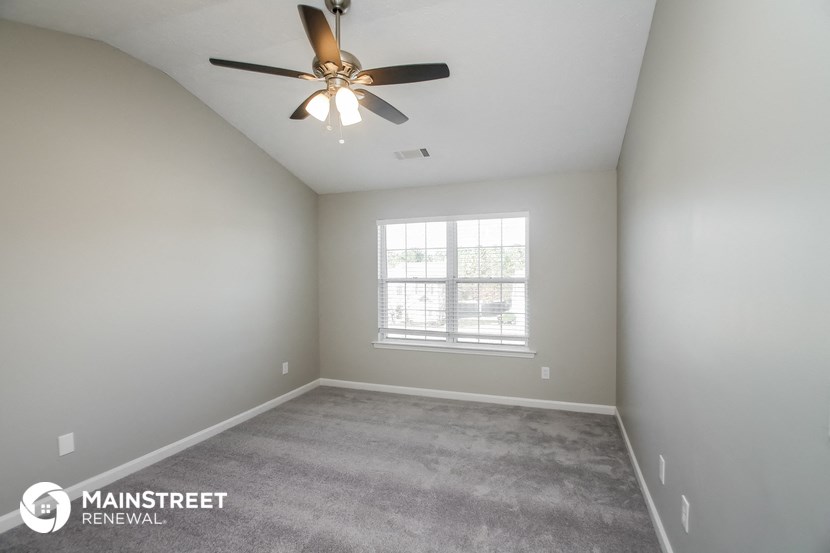 an empty room with a ceiling fan and a window