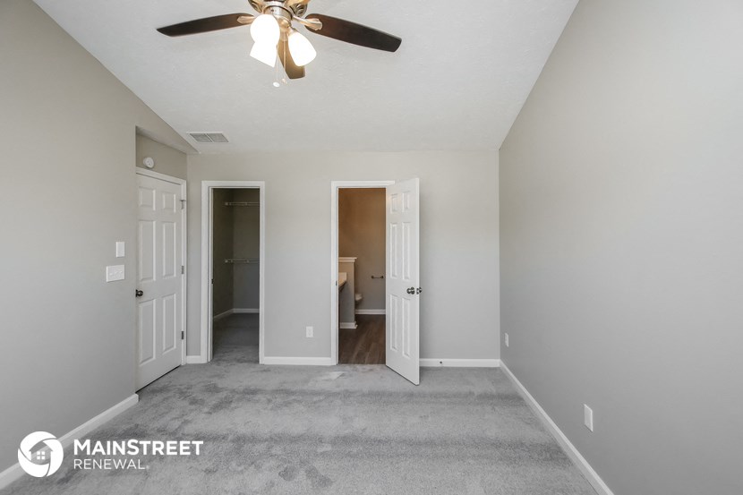 a living room with a ceiling fan and a carpet