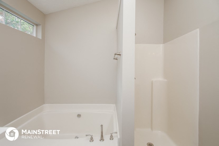 a bathroom with a tub and a shower and a window