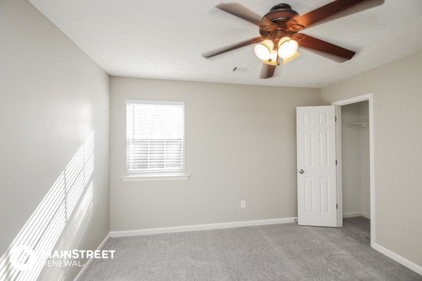 the living room has a ceiling fan and a door to the bedroom