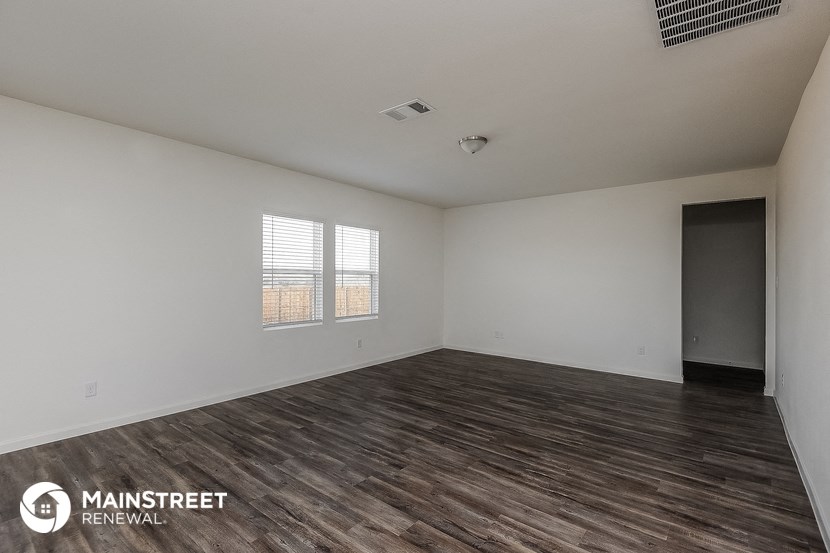 the living room of an apartment with white walls and wooden floors