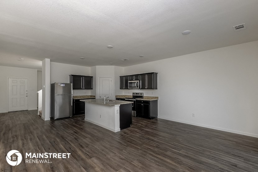 an open kitchen and living room with stainless steel appliances and wood flooring