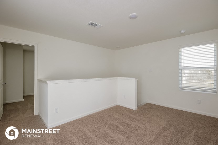 the bedroom of an apartment with white walls and carpet