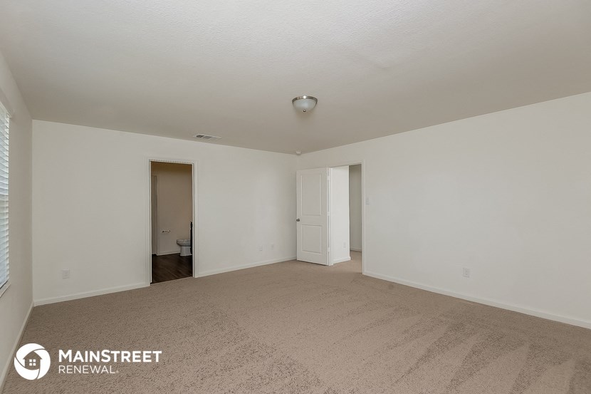 a spacious living room with carpet and white walls