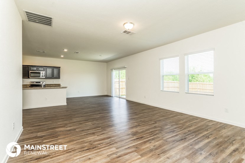 an empty living room and kitchen with wood flooring