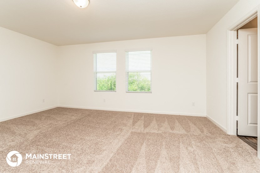 a empty living room with two windows and a door