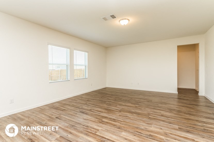 a spacious living room with wood flooring and white walls