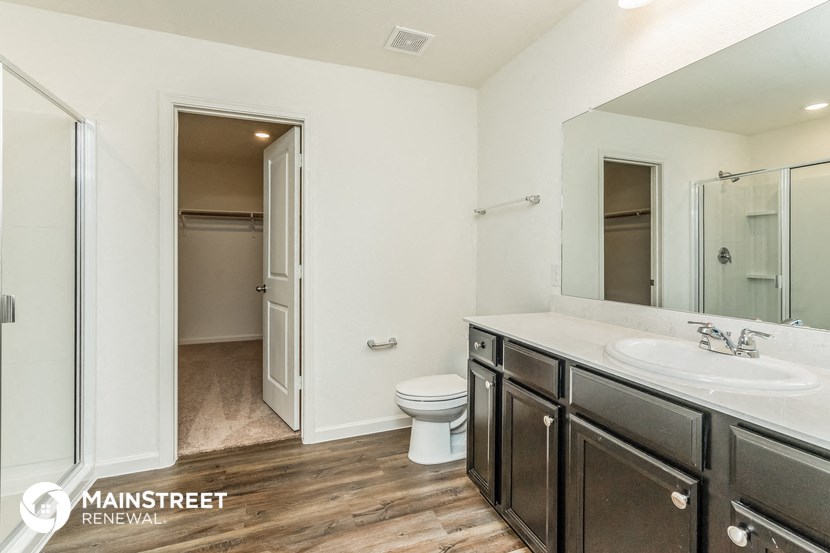 a bathroom with a toilet sink and mirror and a shower