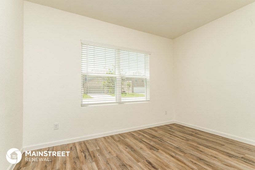 the living room of a home with wood flooring and a window