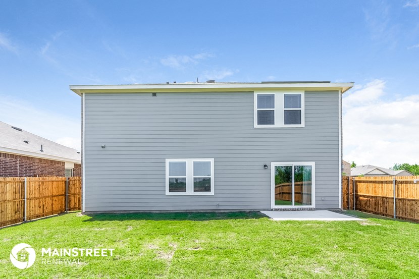 a small gray house with a yard and a wooden fence