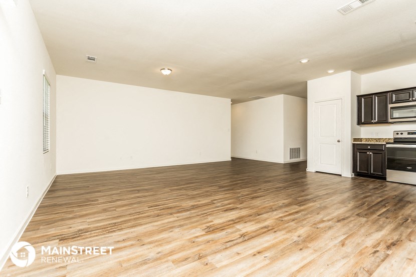the living room and kitchen of an apartment with wood floors and white walls