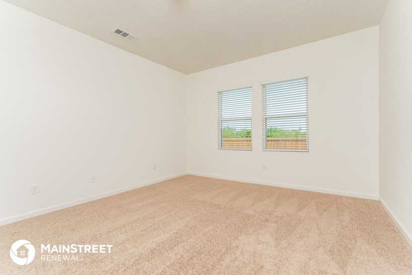 the spacious living room with carpet and two windows