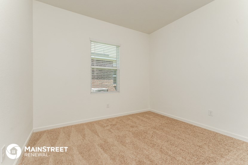 the spacious living room with carpeting and a window