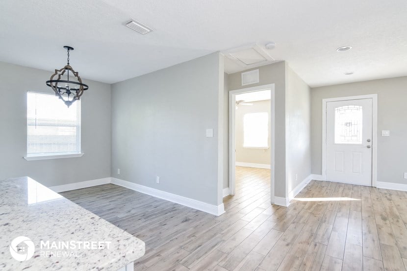 a renovated kitchen and dining room with white walls and wood floors