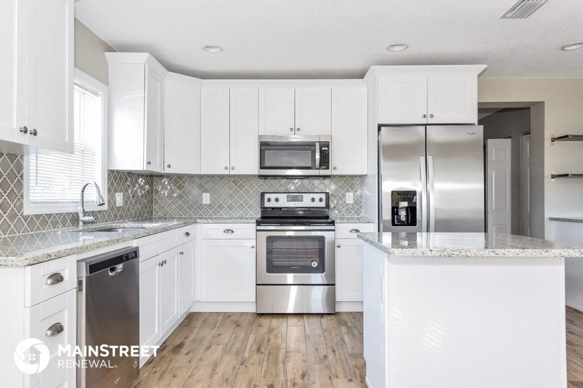 a white kitchen with stainless steel appliances and white cabinets