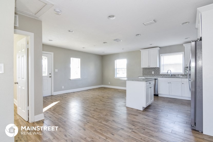 an open kitchen and living room with wood flooring and stainless steel appliances