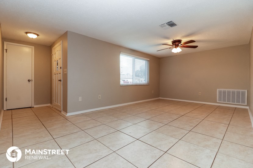 an empty living room with tile flooring and a ceiling fan