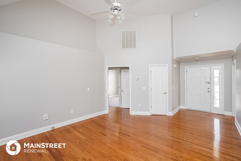 the spacious living room with wood flooring and white walls