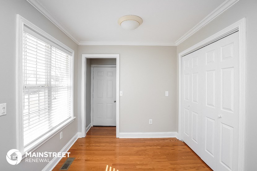 a bedroom with a large window and a door and a wooden floor