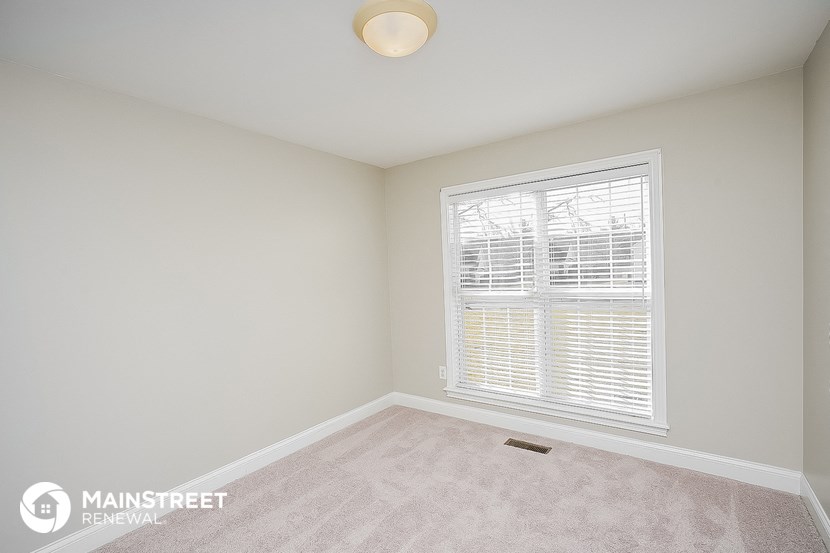 a bedroom with a large window and a carpeted floor