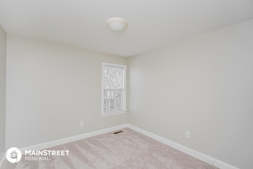 the spacious living room with white walls and carpet