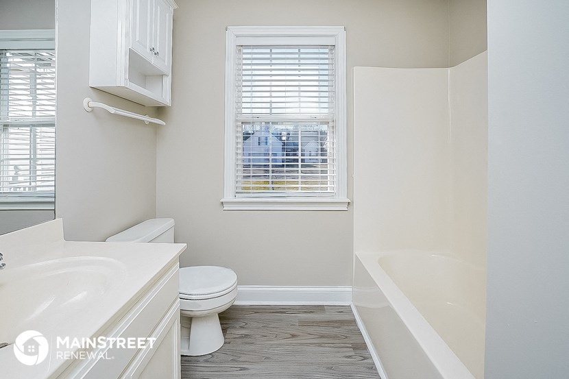 a bathroom with a toilet and a tub and a window