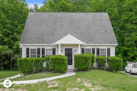 a small white house with bushes in front of it
