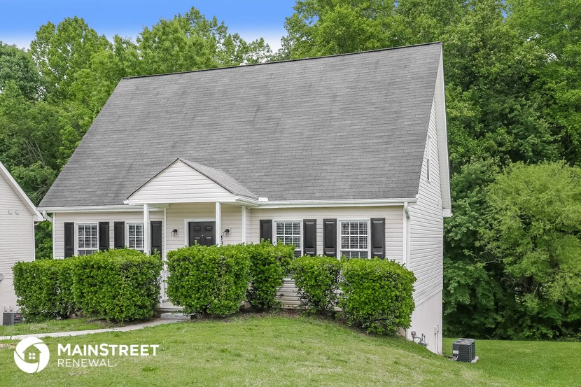 a small white house with bushes in front of it