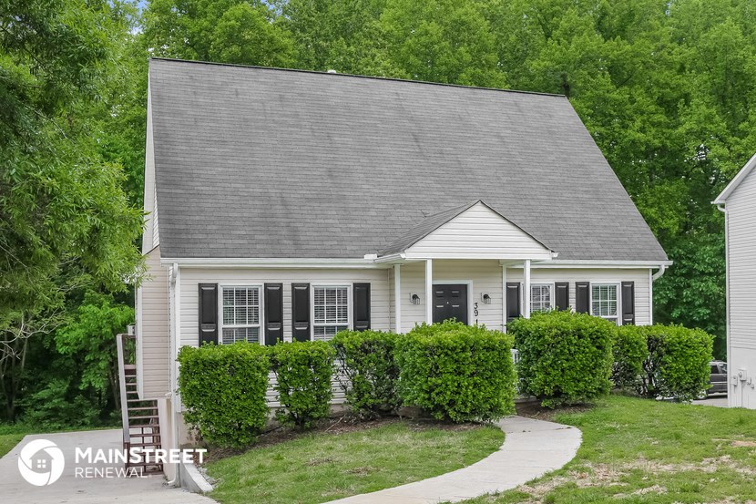 a small white house with bushes in front of it