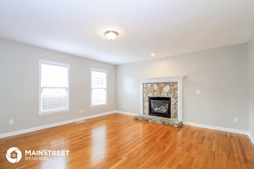 the living room with wood floors and a fireplace