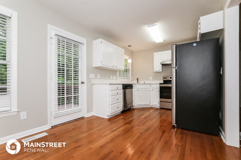 a renovated kitchen with white cabinets and a black refrigerator