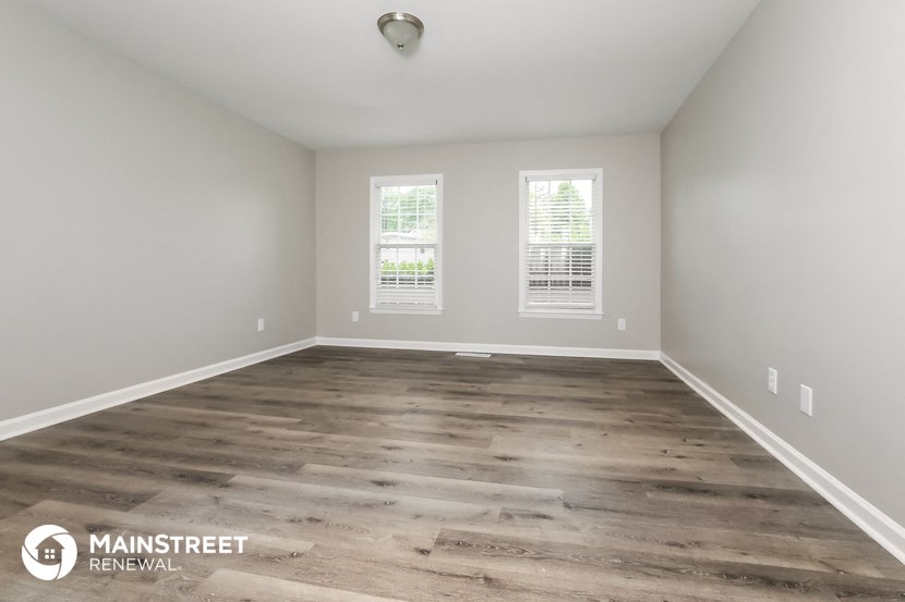 the spacious living room with wood flooring and two windows