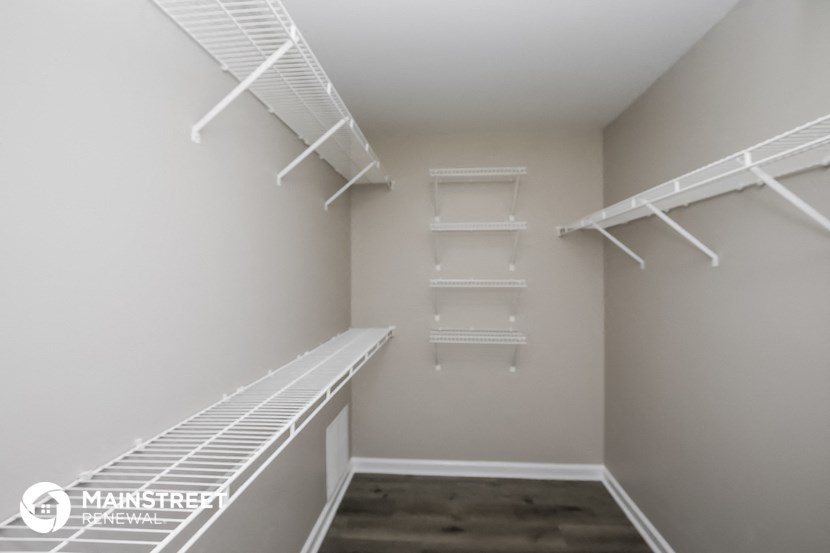 a spacious walk in closet with white shelves and empty shelves