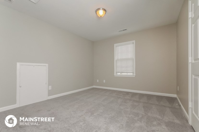 the spacious living room with white walls and gray carpet