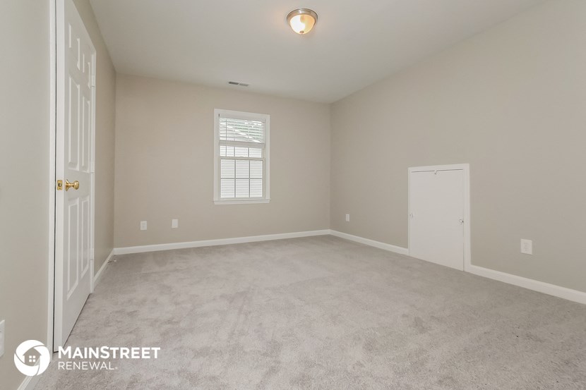 the spacious living room with carpeted flooring and a white door