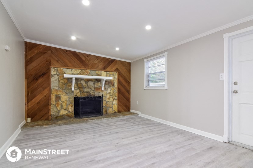 the living room has a stone fireplace and a wood paneled wall
