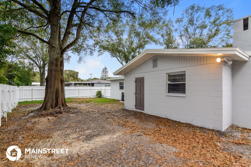 a small white house with a large tree in the yard
