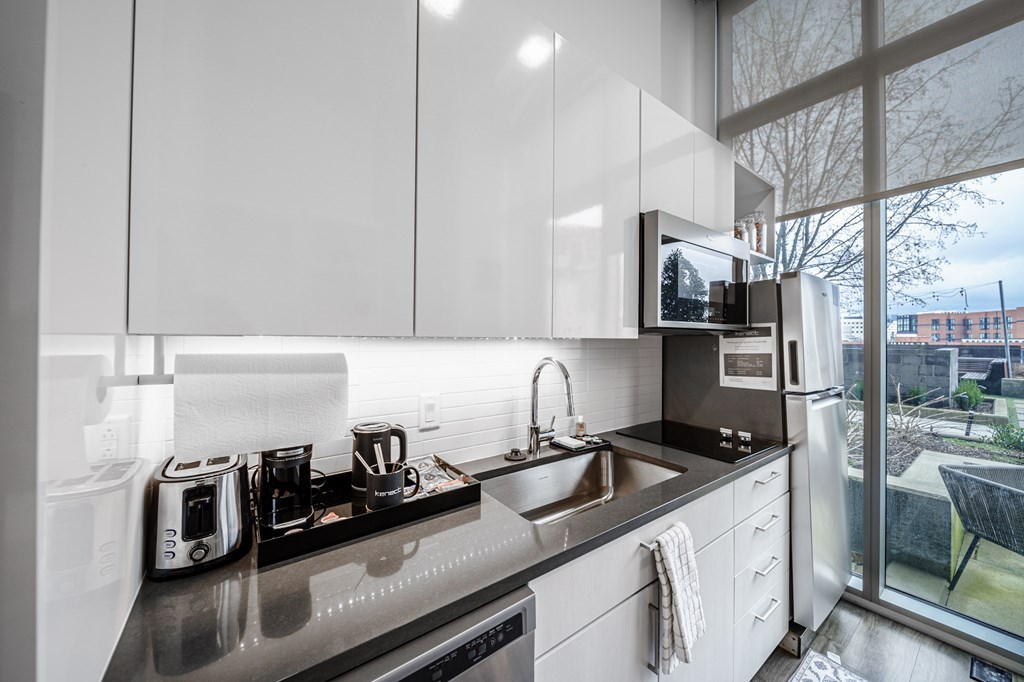 A modern kitchen with a stainless steel countertop and white cabinets.