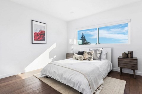 A bedroom with a large bed and a framed picture on the wall.
