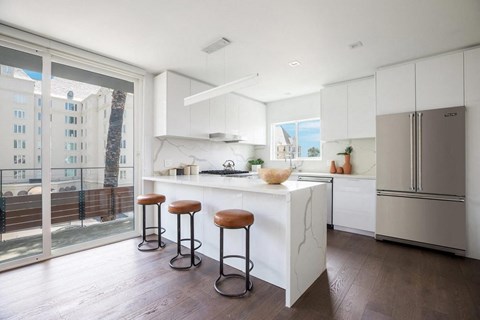 A kitchen with white cabinets and a marble island.
