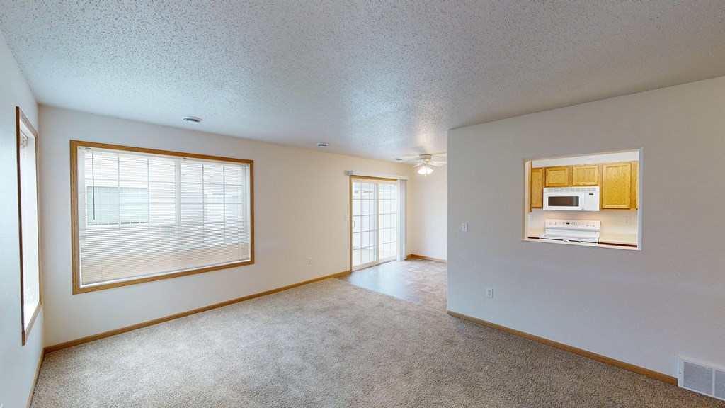 an empty living room with a microwave and a window