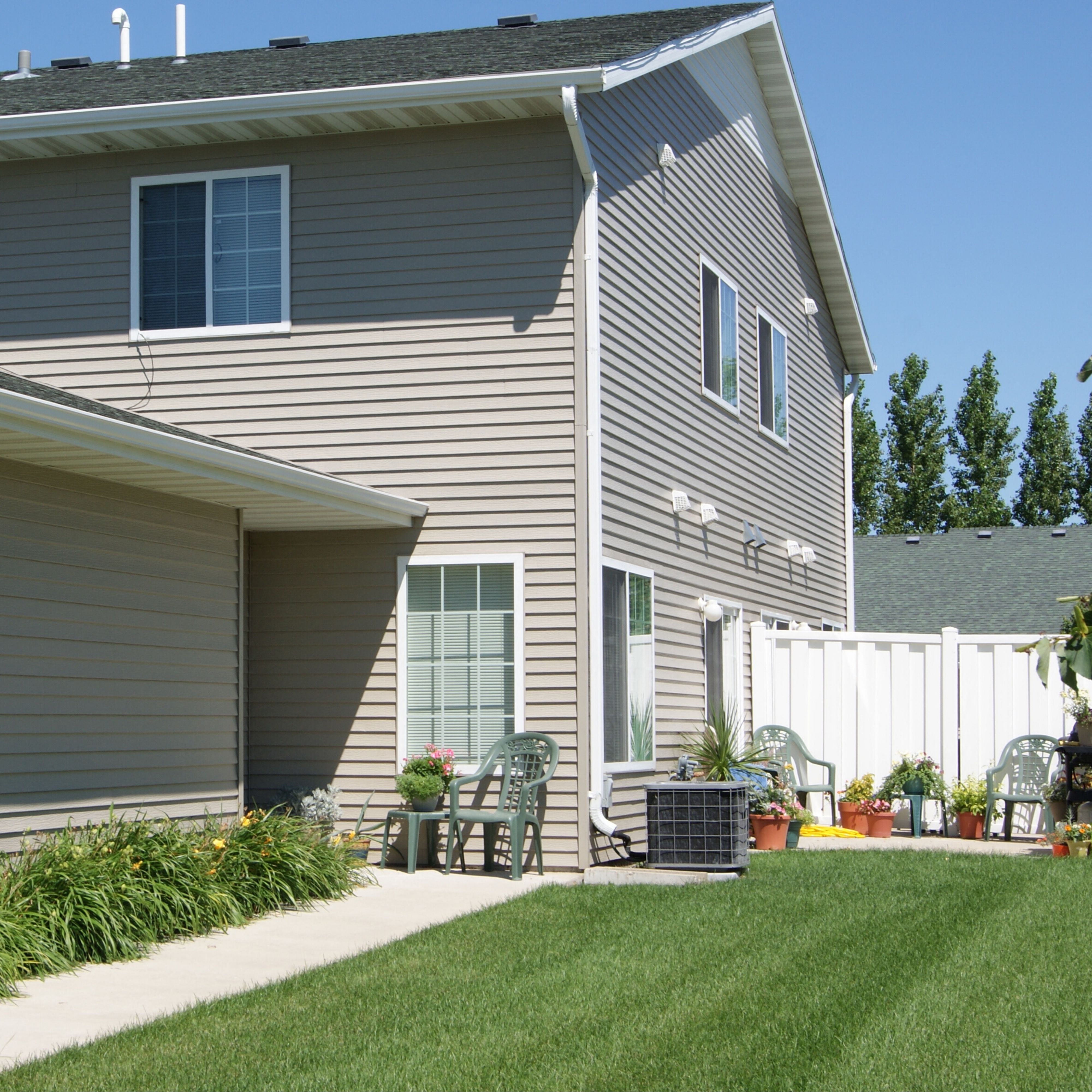 the side of a house with patio furniture and a lawn
