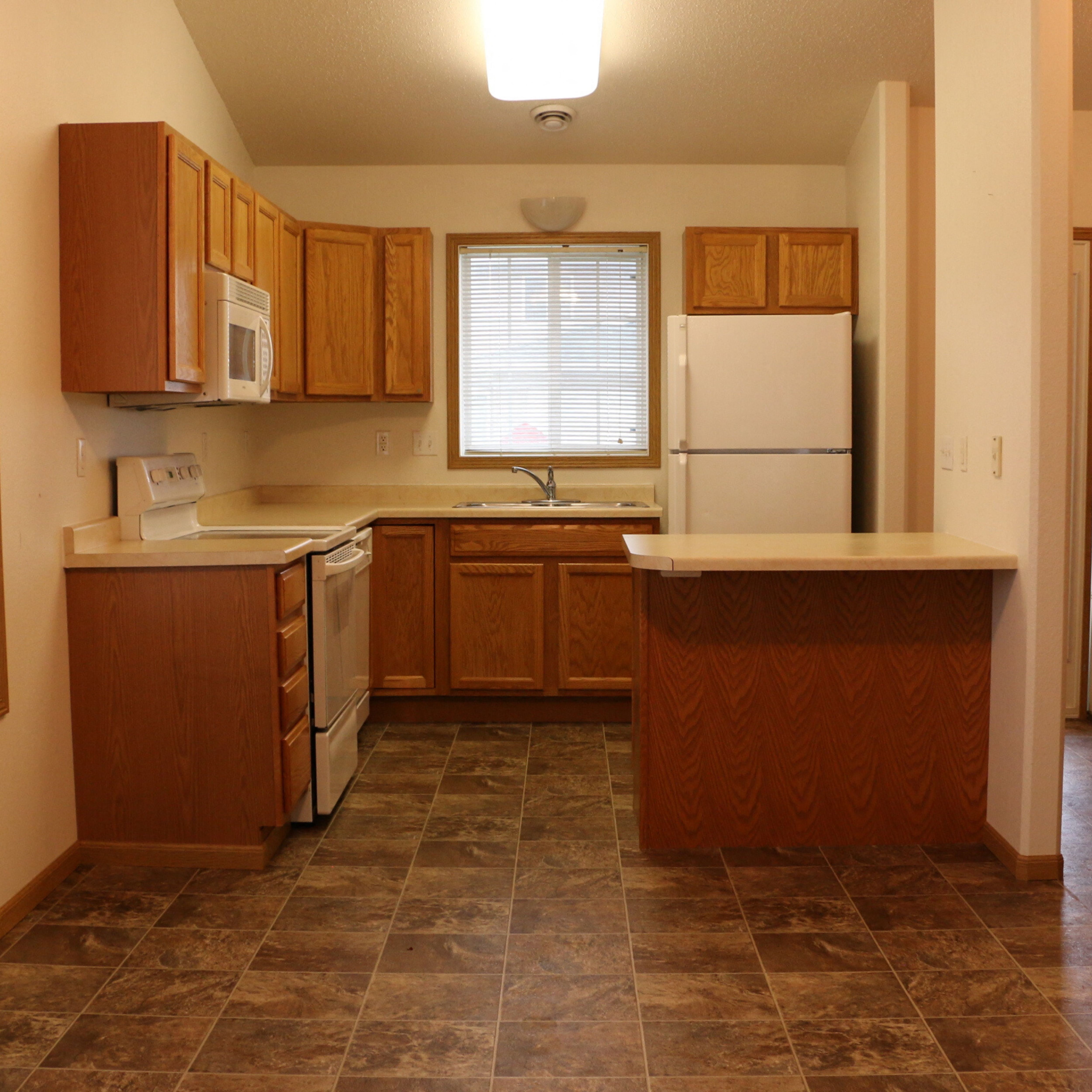 an empty kitchen with wooden cabinets and a white refrigerator