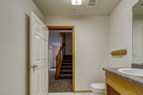 the bathroom door is open to the hallway and the stairs to the bedroom and living
