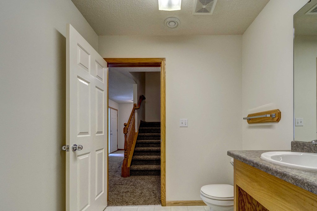 the bathroom door is open to the hallway and the stairs to the bedroom and living