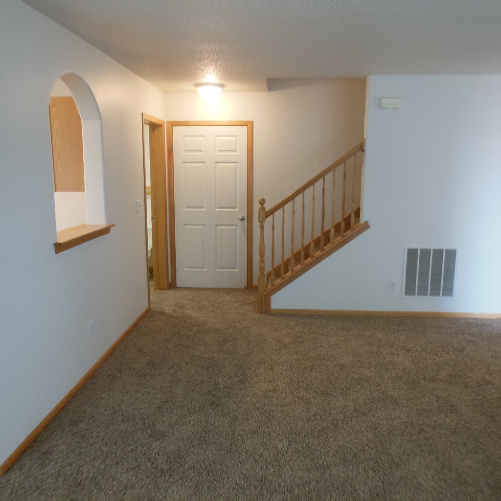 living room an empty living room with a staircase and a white door