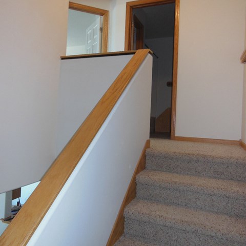 a staircase with a wooden railing and carpeted stairs    and a door