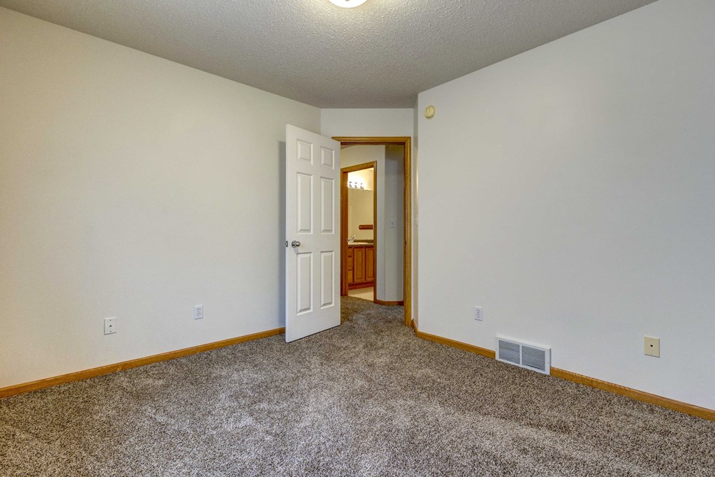a living room with carpet and a door to a bathroom