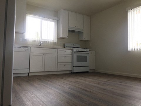an empty kitchen with white cabinets and a stove