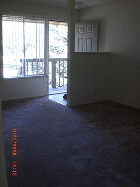 an empty living room with a door to a balcony